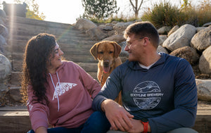 Couple wearing eddyline apparel smiling at their dog