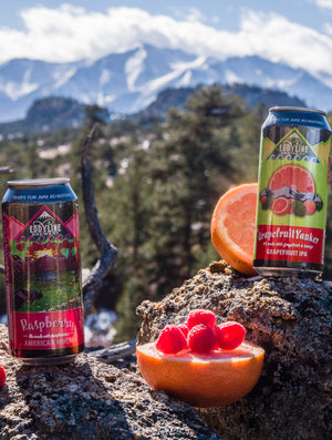 A picture with 16 oz Raspberry wheat on the left and a 16 oz GrapefuitYanker on the right.   In between is a half cut grapefruit with fresh raspberries on top. 